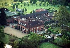 an aerial view of a large brick building in the middle of a lush green field