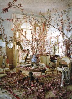 an old black and white photo of a living room with furniture, flowers and mirrors