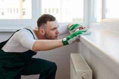 a man with green gloves on leaning against a window sill