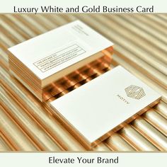 two white and gold business cards sitting on top of each other with the words luxury white and gold business card