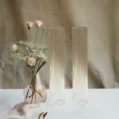 two vases with flowers in them on a table