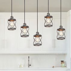 five lights hanging from the ceiling above a kitchen sink and counter top with white cabinets