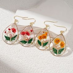 three pairs of dangle earrings with flowers painted on them