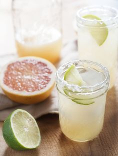 two mason jars filled with lemonade, lime and grapefruits on a wooden table