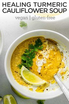 a white bowl filled with soup and garnished with cilantro, parsley and lime