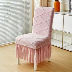 a pink chair with a ruffled skirt on it in front of a white window