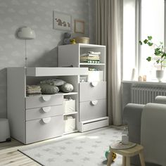 a living room with white furniture and a baby's crib in the corner