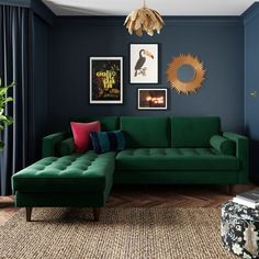 a living room with dark blue walls and green couches in front of the window