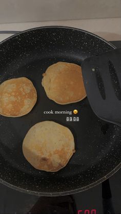 three pancakes frying in a pan on the stove top with a black spatula