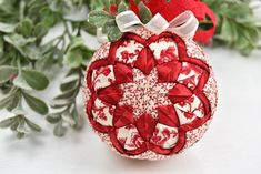 a red and white ornament sitting on top of a table next to green leaves