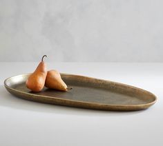 two pears sitting on a plate next to each other in front of a gray background