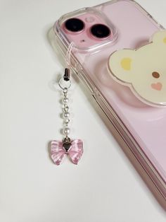 a pink phone case with a keychain attached to it and a teddy bear on the back