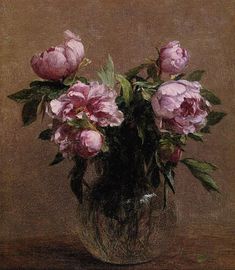 a vase filled with pink flowers on top of a wooden table next to a brown wall