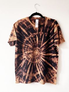 a black and brown tie - dye shirt hanging on a white wall with a hanger