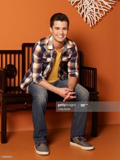 a young man sitting on top of a wooden bench