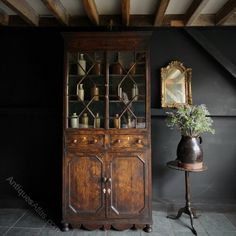 an old wooden cabinet sitting next to a table with a vase on top of it