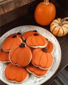 pumpkin shaped cookies on a plate next to small pumpkins