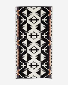 a black and white rug with an orange design on the bottom, in front of a gray background