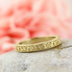 a gold wedding band sitting on top of a rock