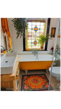 a bathroom with a bathtub, sink and rug in front of a window that has stained glass