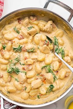 a pot filled with pasta and spinach on top of a table