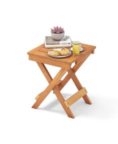 a small wooden table with food on it and a bowl of fruit next to it