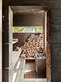 the inside of a cabin with wood stacked up