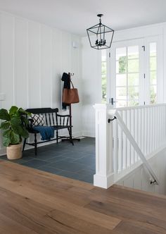 a room with white walls and wood flooring next to a stair case in front of a window