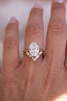 a woman's hand with a diamond ring on top of her finger and an engagement band