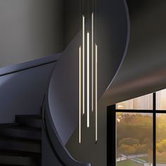 a modern light fixture hanging from the ceiling in a room next to a window and stairs