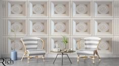 two chairs sitting next to each other in front of a wall with decorative tiles on it