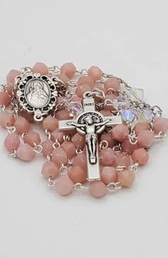 "This one-of-a-kind rosary captures the timeless elegance of pink opals and Swarovksi crystals.     The \"Hail Mary\" beads are natural pink opal stones, laced in stainless steel wire.    Each \"Our Father\" bead is an authentic Swarovski crystal laced in stainless steel wire and linked to stainless steel chain.    The centerpiece is authentic Italian (Italy marked) metal with an engraved image of \"The Sacred Heart of Jesus.\"   The crucifix features the Saint Benedict medal of protection engra Spiritual Pink Crystals Gemstone, Pink Spiritual Gemstone Crystals, Handmade Pink Rosary For Healing, Pink 8mm Beads Crucifix Jewelry, Handmade Pink Spiritual Crystals, Rosary Gift, Crystal Lace, Rosary Bracelet, Heart Of Jesus