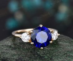 a blue and white diamond ring on top of a rock