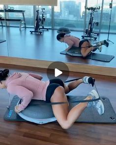 a woman laying on top of a gym mat in front of another woman with dumbbells