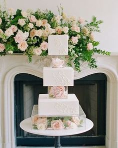 a three tiered wedding cake sitting on top of a table next to a fireplace