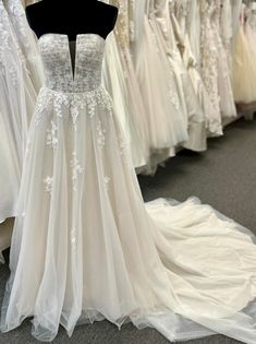 a wedding dress on display in a store with other gowns and dresses behind it