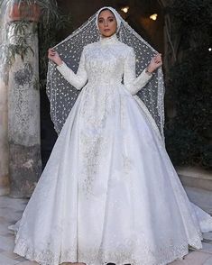 a woman in a white wedding gown and veil standing on a tile floor with her hands on her hips