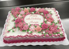 a pink and white birthday cake with flowers on it