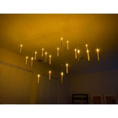 a chandelier made out of candles hanging from the ceiling in a room with blinds