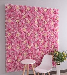 a pink flowered wall in the corner of a room with two chairs and a table