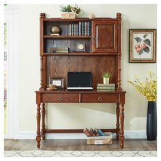 a wooden desk with a laptop on top of it and bookshelf in the background