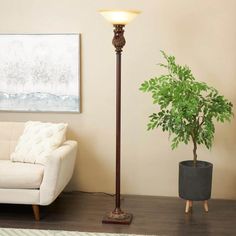 a living room with a white couch and a potted plant on the floor next to a lamp