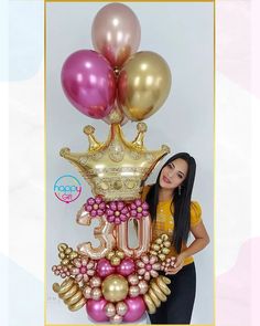 a woman standing in front of balloons with the number twenty five on it and a crown