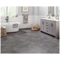 a bathroom with gray tile floors and white walls, along with a large bathtub