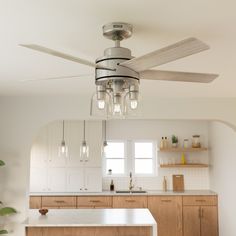 a ceiling fan in a kitchen with wooden cabinets and white counter tops on the island