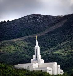 a large white building sitting on top of a lush green hillside