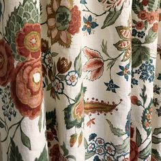 the curtain is decorated with colorful flowers and leaves on white fabric, as well as an orange flower