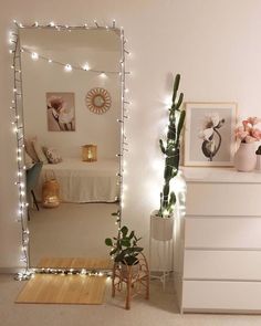 a bedroom decorated with lights and plants on the wall, along with a mirror that has been placed in front of it