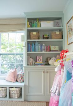 a room with lots of books and toys on the shelves in front of a window