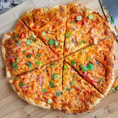 a sliced pizza sitting on top of a wooden cutting board next to a spatula